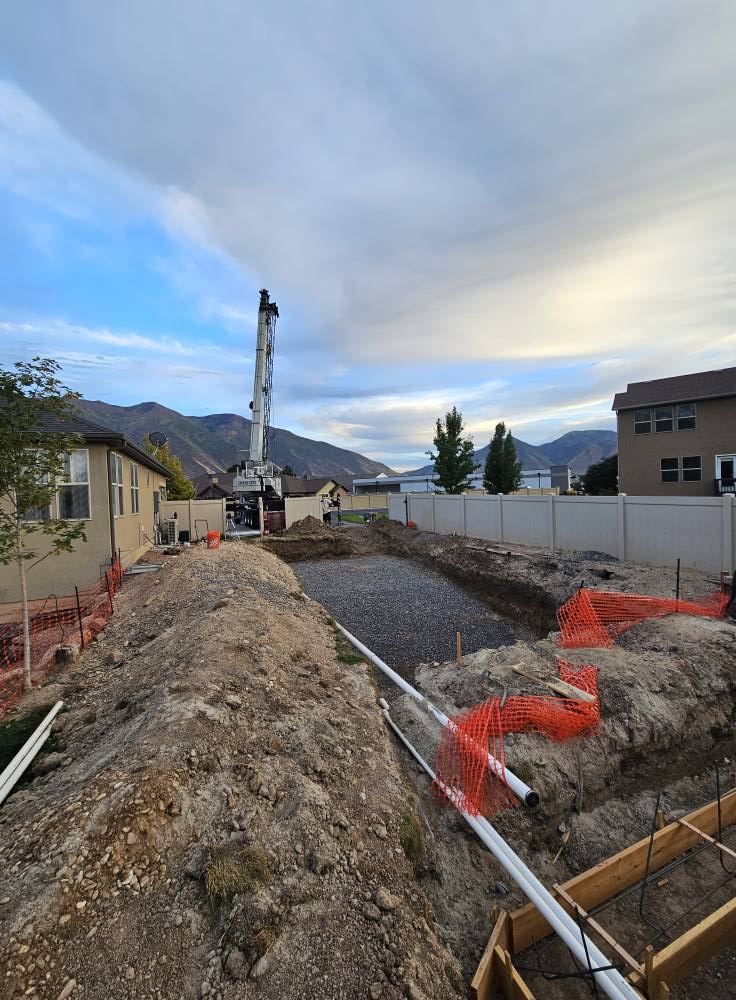 Crane staged for fiberglass shell drop after backyard excavation