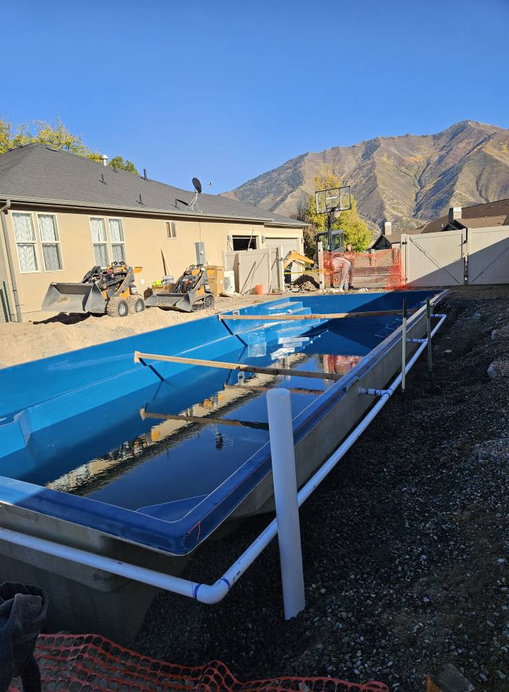 Fresh fiberglass pool shell delivered on-site with mountain backdrop