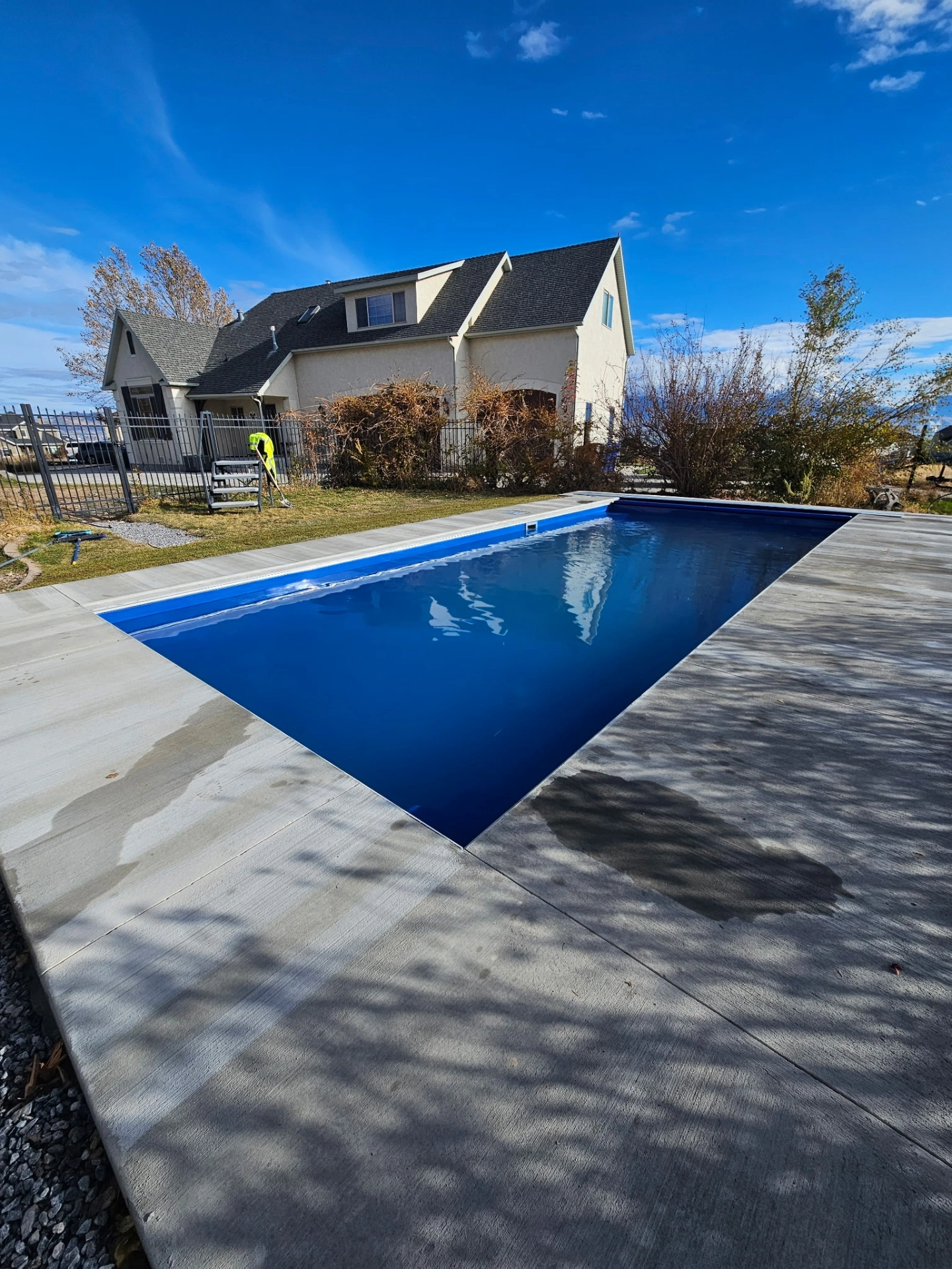 Deep blue fiberglass pool with crisp concrete deck on a clear Utah day