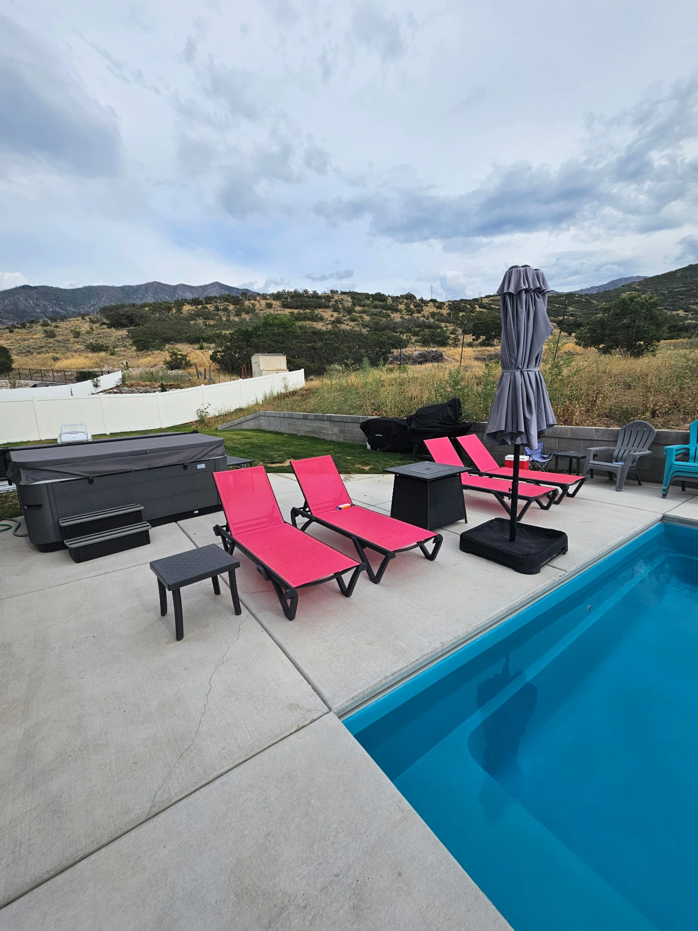 Backyard pool with hot tub, lounge seating, and Utah foothill views
