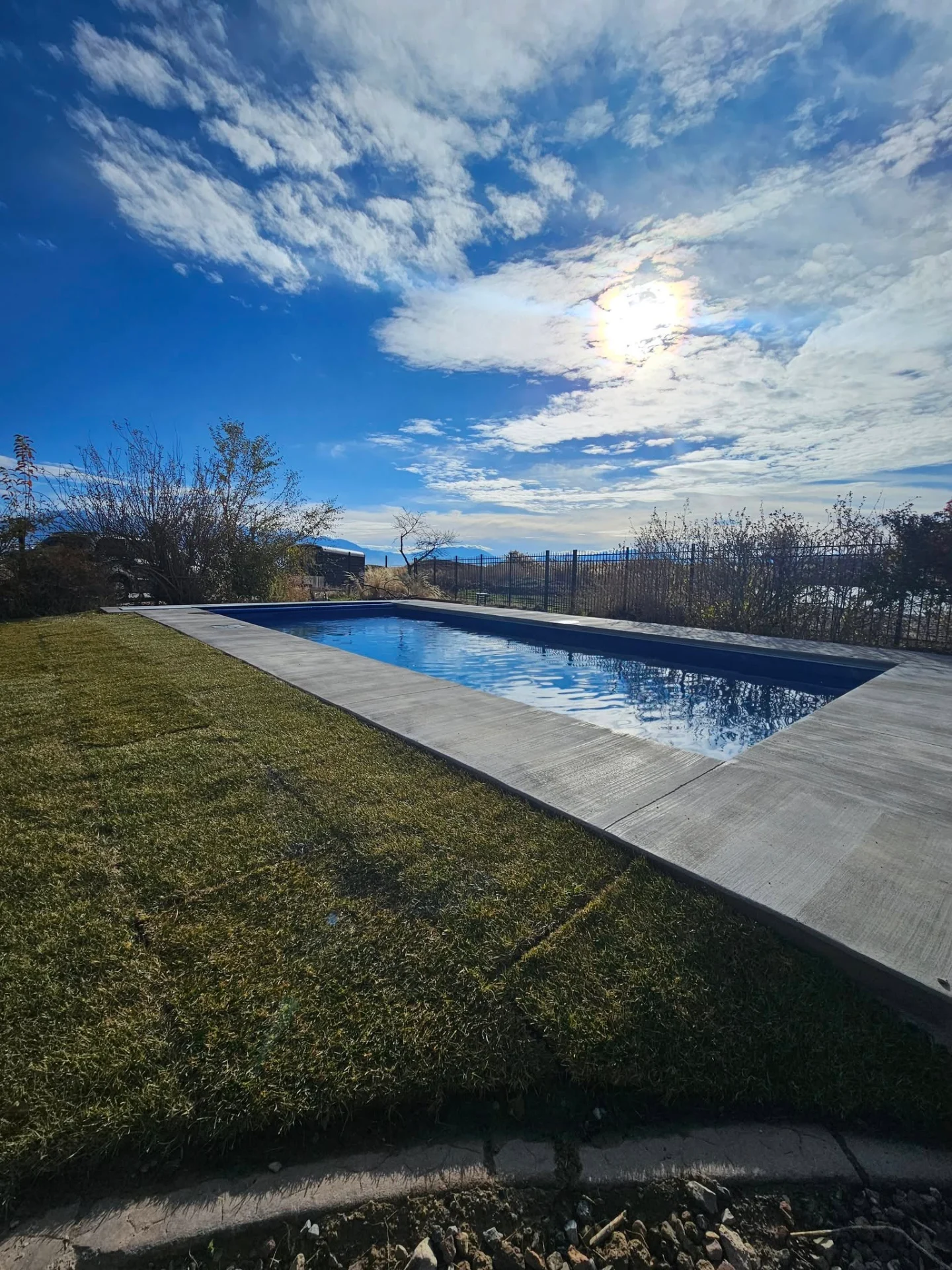 Completed fiberglass pool with custom concrete deck and Utah mountain views