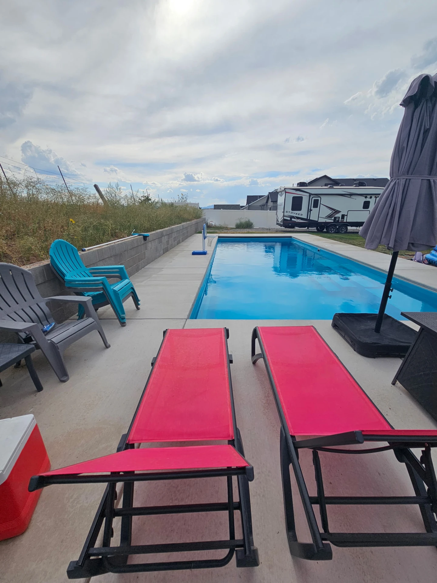 Poolside lounge setup with chaise chairs and umbrella shade