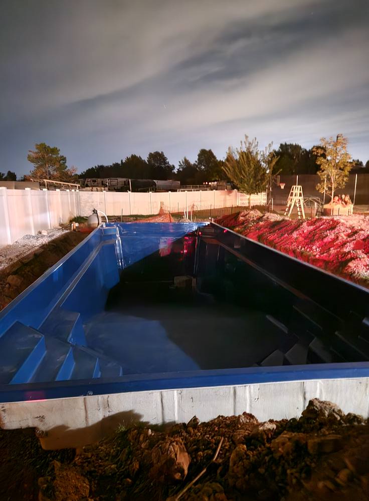 Fiberglass shell set in place at dusk, ready for plumbing and backfill